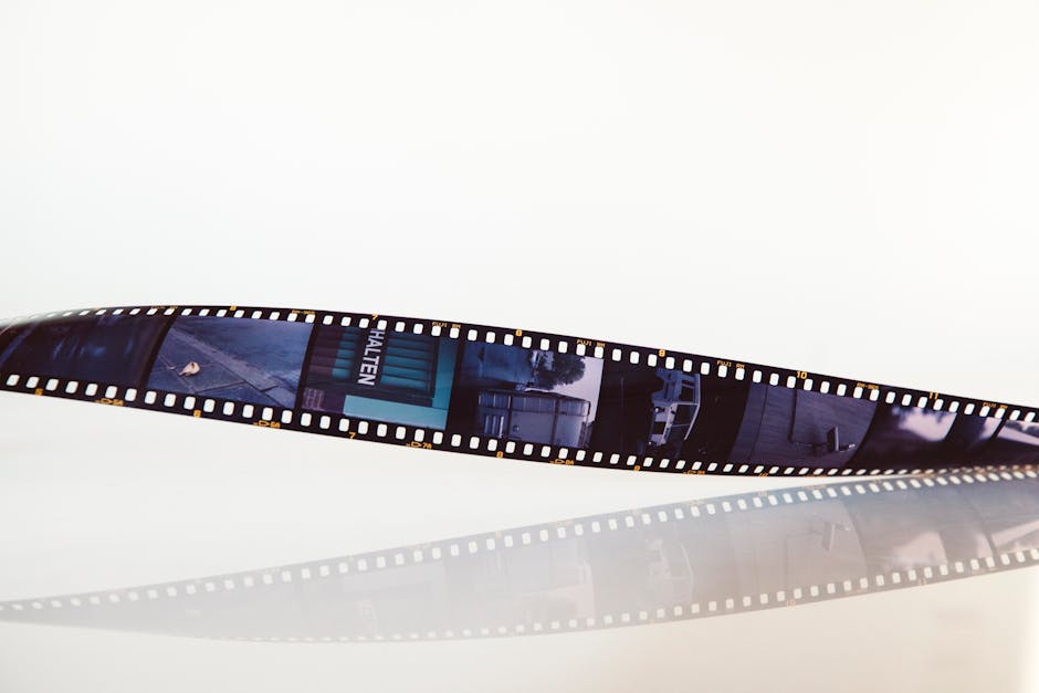 Close-up of a vintage film strip on a white reflective background, conveying nostalgia.